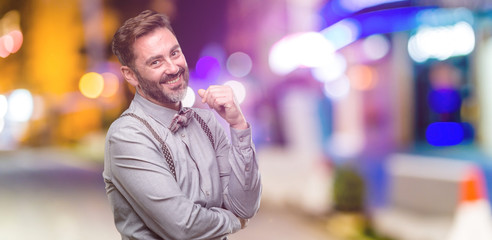 Fototapeta premium Middle age man, with beard and bow tie confident and happy with a big natural smile laughing at night club