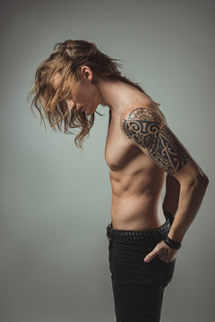 sexy shirtless man with tattoo posing in black jeans, isolated on grey