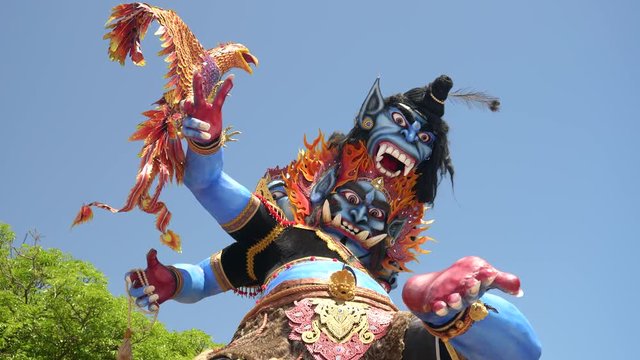 a low angle shot of an ogoh-ogoh statue with a garuda at kuta beach in bali, indonesia