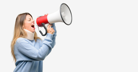 Young injured woman wearing neck brace collar communicates shouting loud holding a megaphone, expressing success and positive concept, idea for marketing or sales