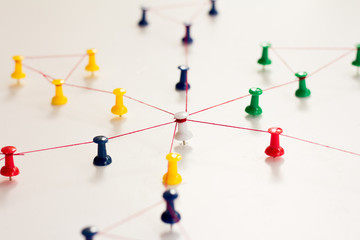 Linking entities. Monotone. Networking, social media, SNS, internet communication abstract. Small network connected to a larger network. in paper linked together by cotton with a red yarn 
