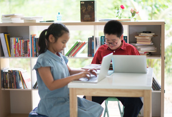 Students boy and girl in the library read books and ebook for education