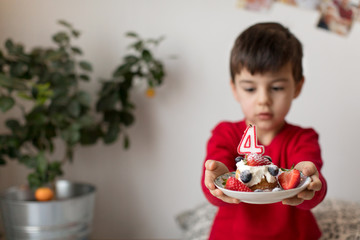 Young boy holding birthday cupcake