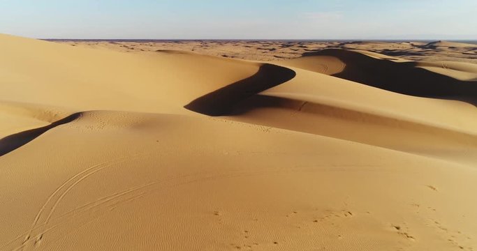 Aerial view flying over sand dunes in desert at sunset