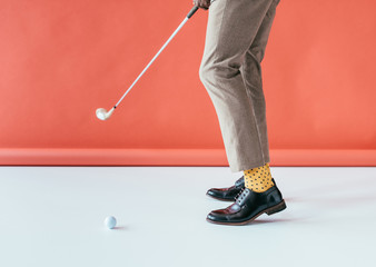 Fototapeta na wymiar low section view of golfer with golf club and ball, on red