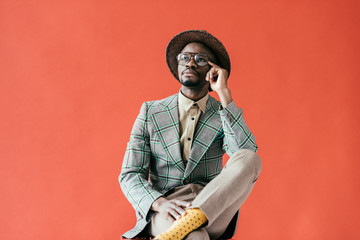 african american man in vintage eyeglasses talking on smartphone, isolated on red - Powered by Adobe