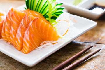 Sashimi, Salmon, Japanese food chopsticks and wasabi on the wood table
