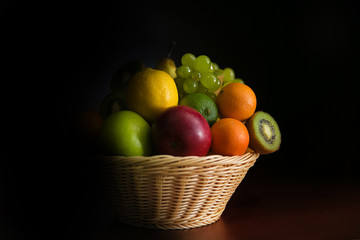 Basket with fruits on a dark background.