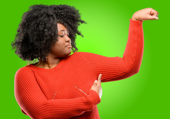 Beautiful african woman pointing biceps expressing strength and gym concept, healthy life its good