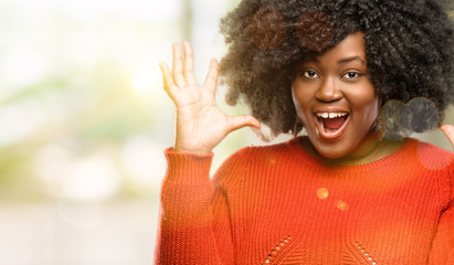 Beautiful african woman happy and surprised cheering expressing wow gesture, outdoor