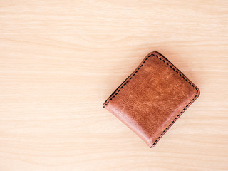Brown wallet on wood table background.