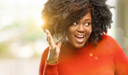 Beautiful african woman happy and surprised cheering expressing wow gesture, outdoor