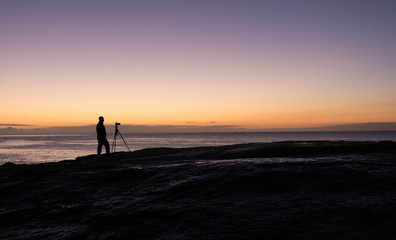 Fototapeta premium Photographer at dawn at the Bow Hole, Tasmania