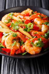 Portion of spicy shrimp with pepper, garlic, corn cob and herbs close-up. vertical