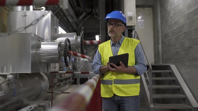 Industrial technician connected with tablet in recyling plant
