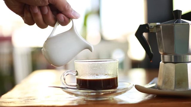 Hand pouring the coffee into a glass.