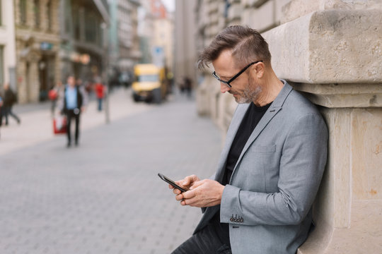 Street portrait of mature man using mobile phone