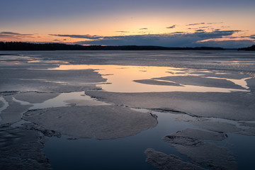 Scenic spring landscape with melted ice and sunset at evening light in Finland