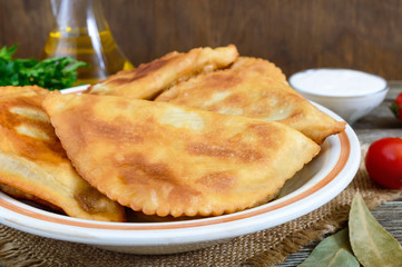 Juicy golden chebureks on a wooden table. Traditional Turkic-Mongolian dish. Street food. Bistro.
