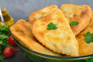 Juicy golden chebureks on a wooden table. Traditional Turkic-Mongolian dish. Street food. Bistro.