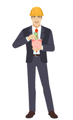 Businesswoman in construction helmet puts banknote in a piggy bank