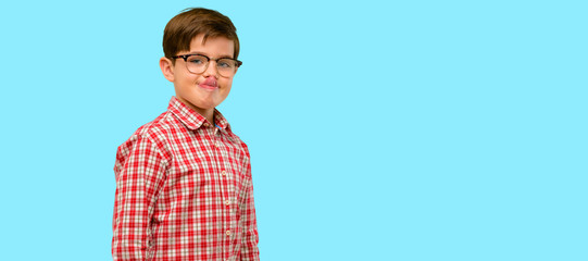 Handsome toddler child with green eyes sticking out tongue at camera at sign of disobedience,...