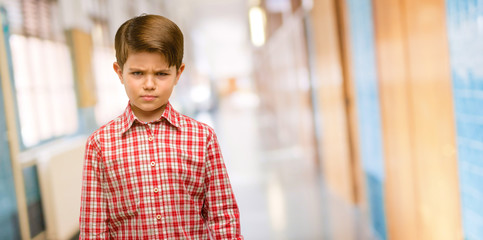 Handsome toddler child with green eyes irritated and angry expressing negative emotion, annoyed with someone at school corridor