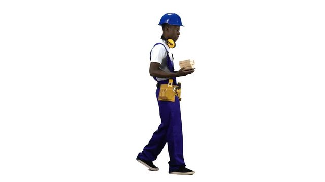 African American builder goes to work with wooden planks in his hands. Alpha channel. Side view