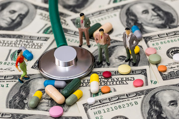 small people on dollar with pills and stethoscope