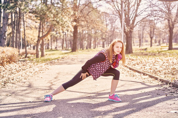 Beautiful sportswoman with smartphone exercising in park