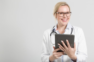 Lächelnde hübsche Ärztin mit Stethoskop und pad