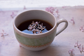 Purple lilac flowers and cup of tea on light wooden background/ teatime/ spring background/ cozy at home/ home spring decoration
