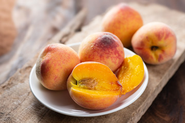 Naklejka na ściany i meble Ripe peaches on white dish and wooden, tropical fruit
