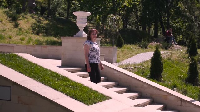 Young woman descends stone stairs in a sity parck