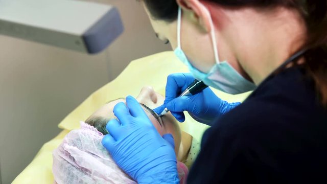 Closeup permanent makeup. Cosmetologist applying permanent tattooing of eyebrows in beauty salon. Microblading workflow