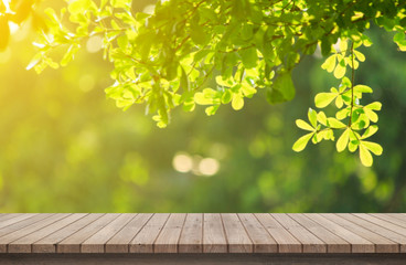 Naklejka na ściany i meble Wood floor with blurred trees of nature park background and summer season, product display montage