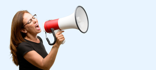 Middle age woman wearing black shirt and glasses communicates shouting loud holding a megaphone, expressing success and positive concept, idea for marketing or sales isolated blue background