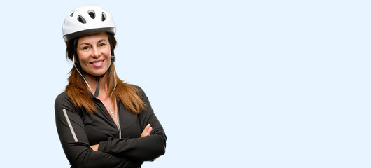Obraz premium Middle age cyclist woman using earphones with crossed arms confident and happy with a big natural smile laughing isolated blue background