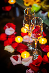 close-up two glasses for champagne, candles and rose petals