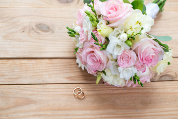 Two gold wedding rings and beautiful wedding are on the brown wood table