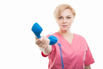 Female nurse wearing pink scrubs handing telephone receiver