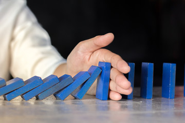 Stop domino risk effect ,businesswomen using hand for management solution.