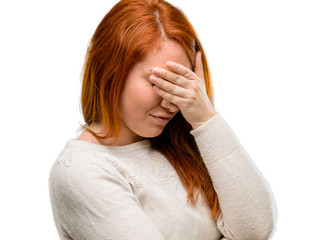 Beautiful young redhead woman stressful keeping hands on head, tired and frustrated isolated over...