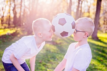 Obraz premium Boys brothers playing with ball on green grass in park.
