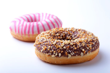 Assorted doughnuts in the glaze, colorful sprinkles and nuts on a white background.