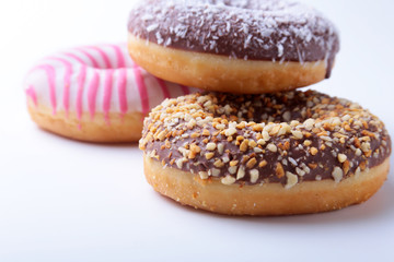 Assorted doughnuts in the glaze, colorful sprinkles and nuts on a white background.