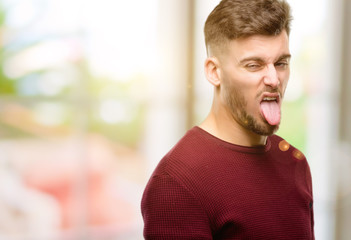 Handsome young man feeling disgusted with tongue out