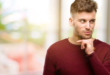 Handsome young man thinking thoughtful with smart face, expressing question and doubt. Imagine the solution