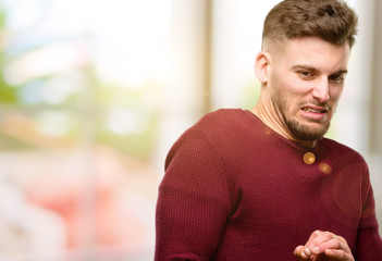 Handsome young man disgusted and angry, keeping hands in stop gesture, as a defense, shouting