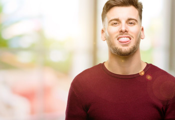 Handsome young man sticking out tongue at camera at sign of disobedience, protest and disrespect